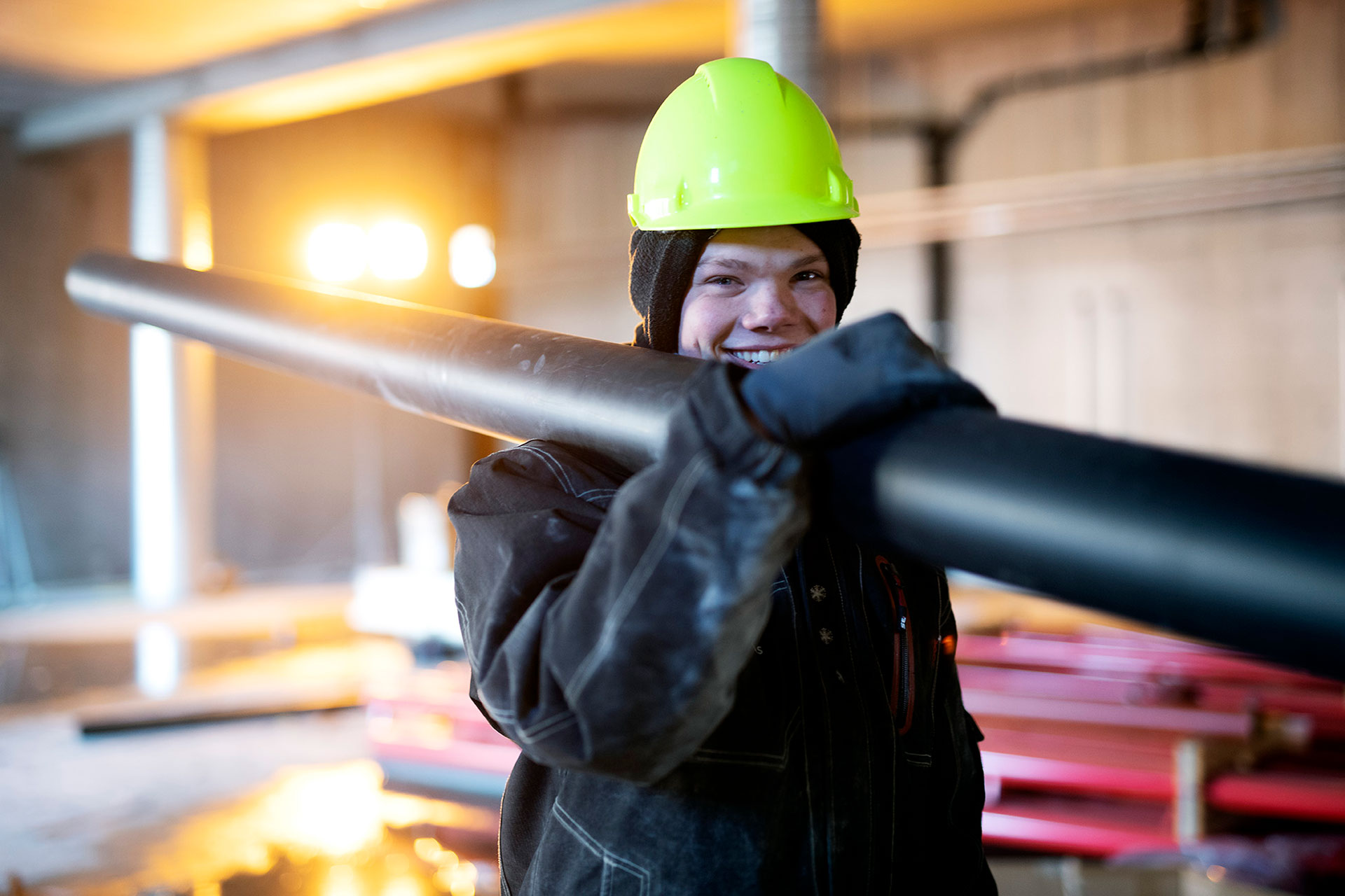 Rørlegger fra Weddes Rørservice bærer rør på skuldera